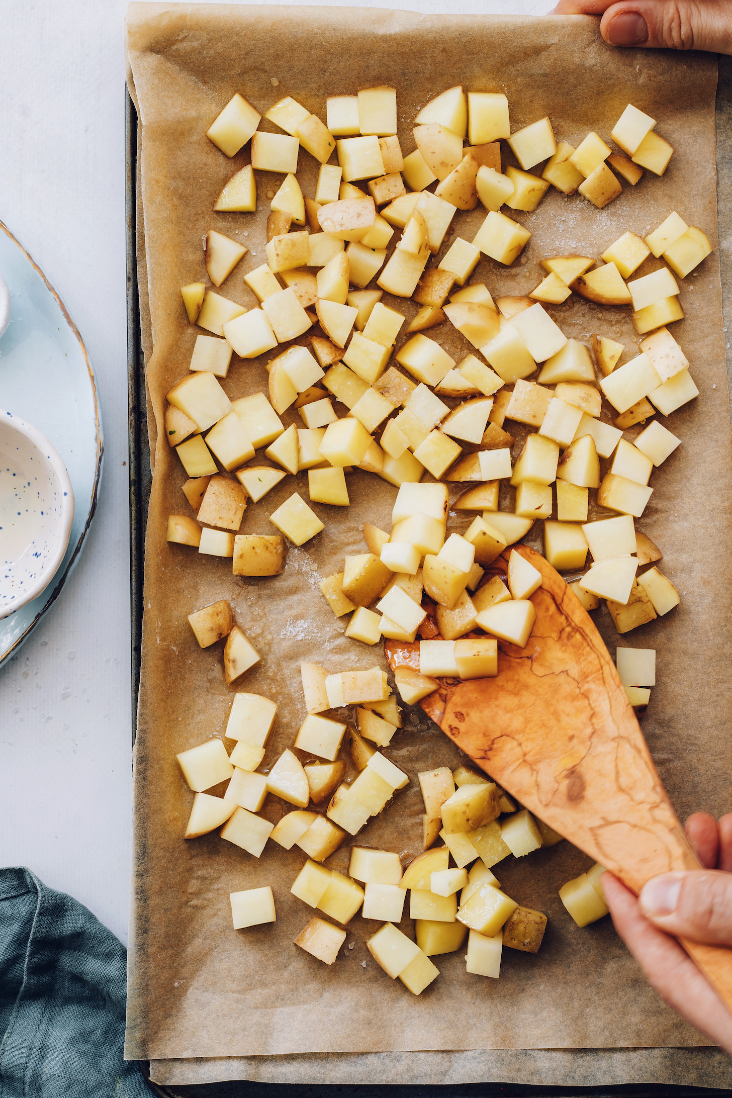 Tossing cubed potatoes with avocado oil and salt