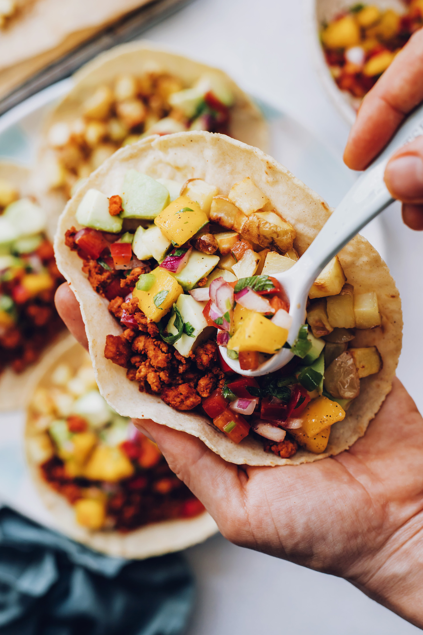 Using a spoon to add mango salsa to a breakfast taco