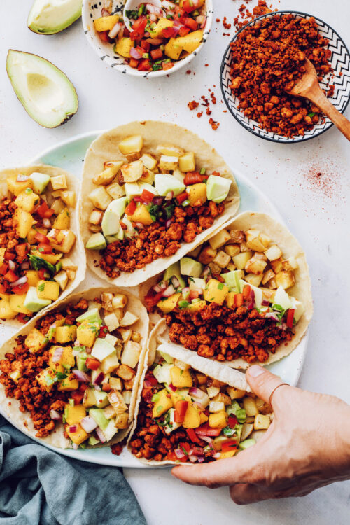 Hand reaching in to pick up a vegan chorizo breakfast taco