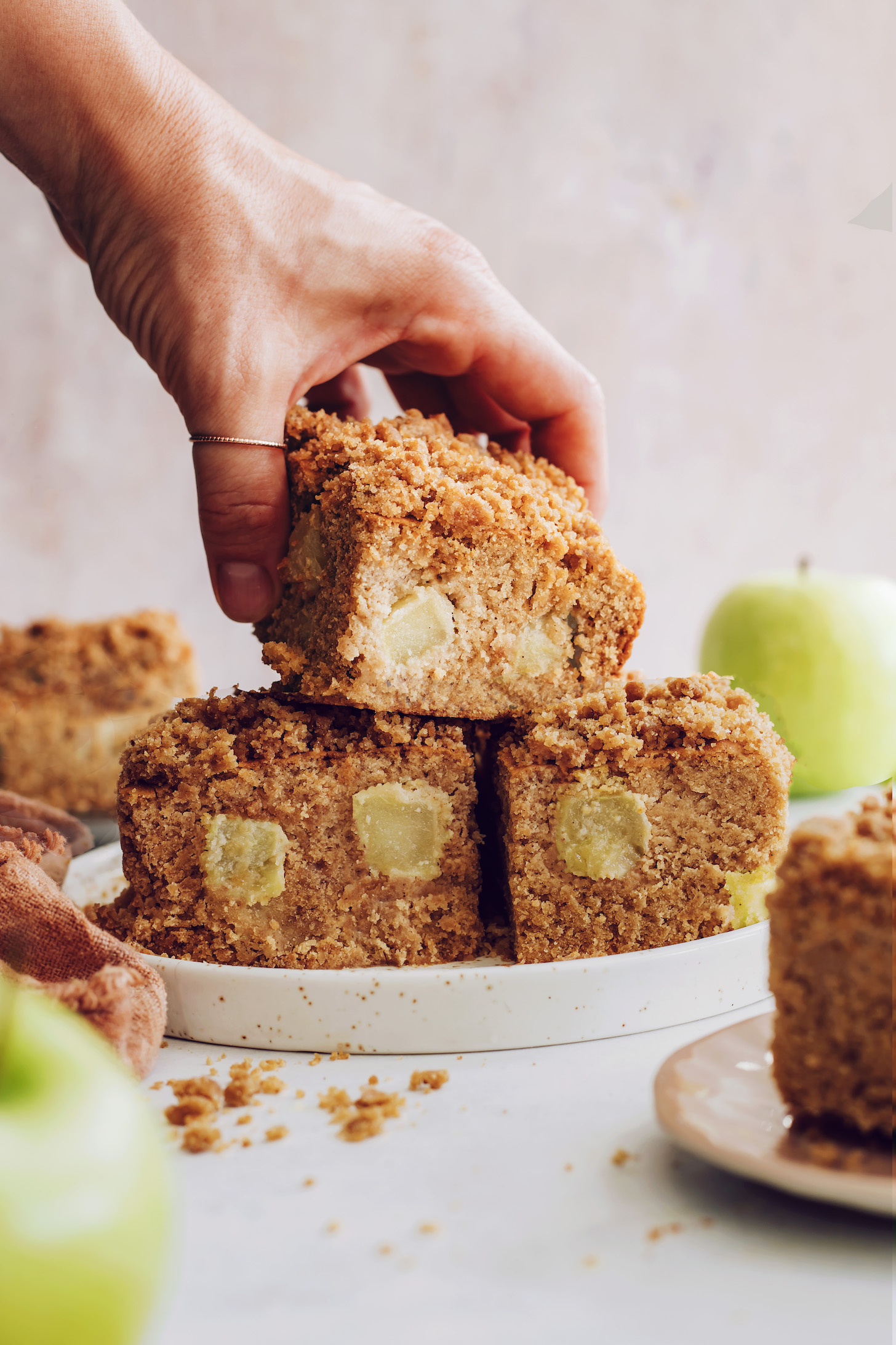 Picking up a slice of apple coffee cake from a plate