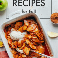 Dish of vegan cinnamon baked apples with vegan vanilla ice cream on top and a spoon in it