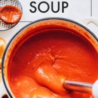 Pot of vegan tomato soup being blended with an immersion blender