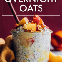 Jar of vegan and gluten-free peaches and cream overnight oats with fresh peaches on top and a spoon in it