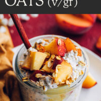 Jar of vegan and gluten-free peaches and cream overnight oats with fresh peaches on top and a spoon in it