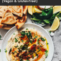 Overhead shot of a bowl of serrano white bean dip next to pita bread