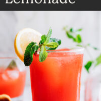 Glass of easy homemade strawberry lemonade with fresh lemon and mint on the side