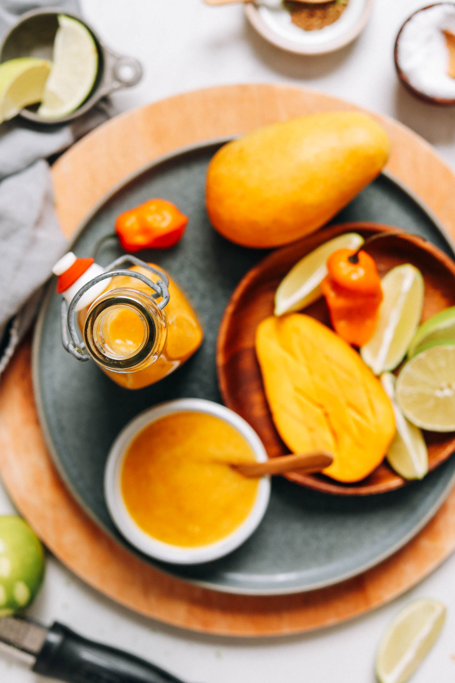 Jar and bowl of mango habanero hot sauce next to ingredients used to make it