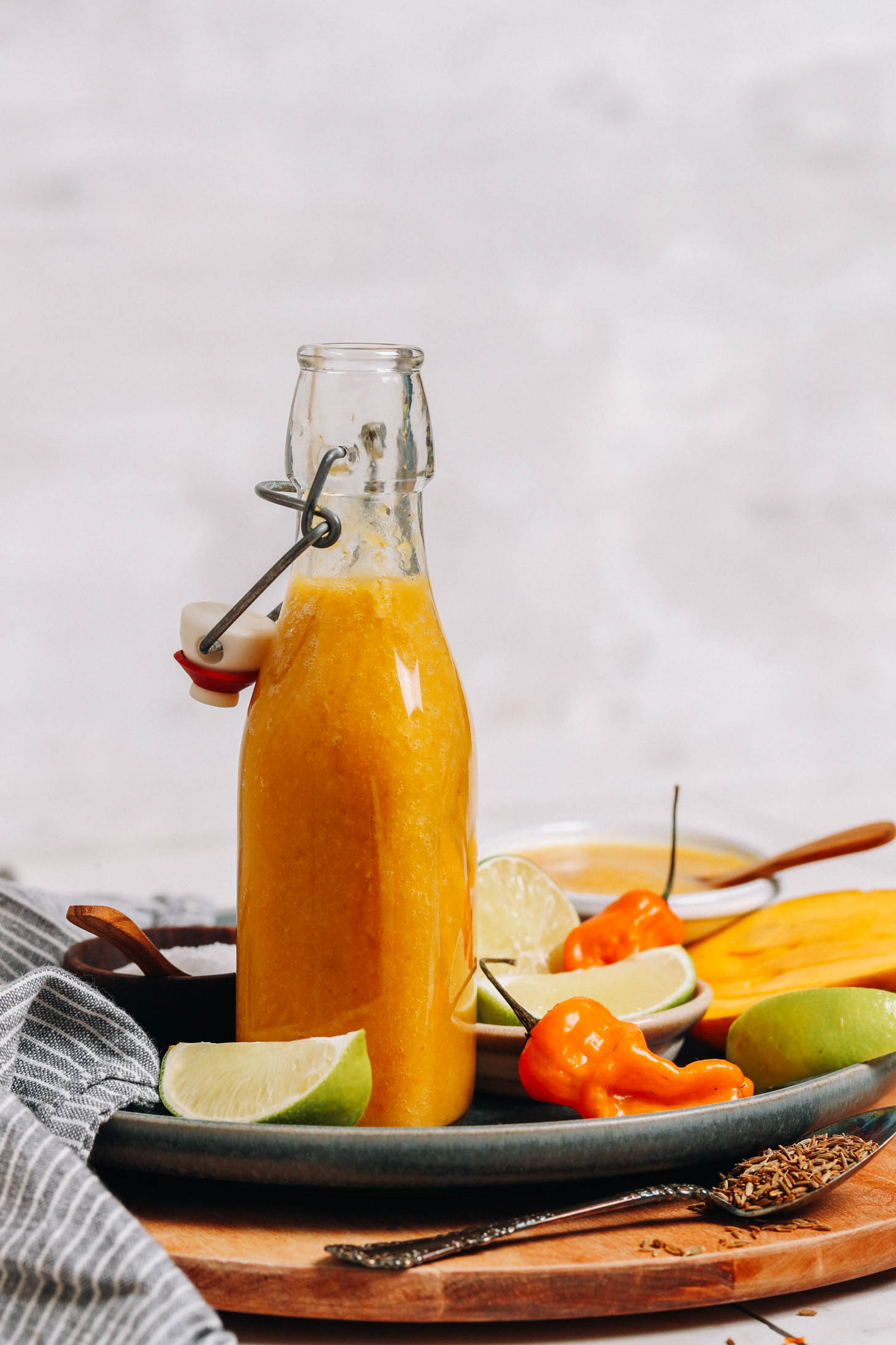 Open bottle of homemade habanero hot sauce on a plate with ingredients used to make it