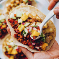 Using a spoon to add mango salsa to a breakfast taco