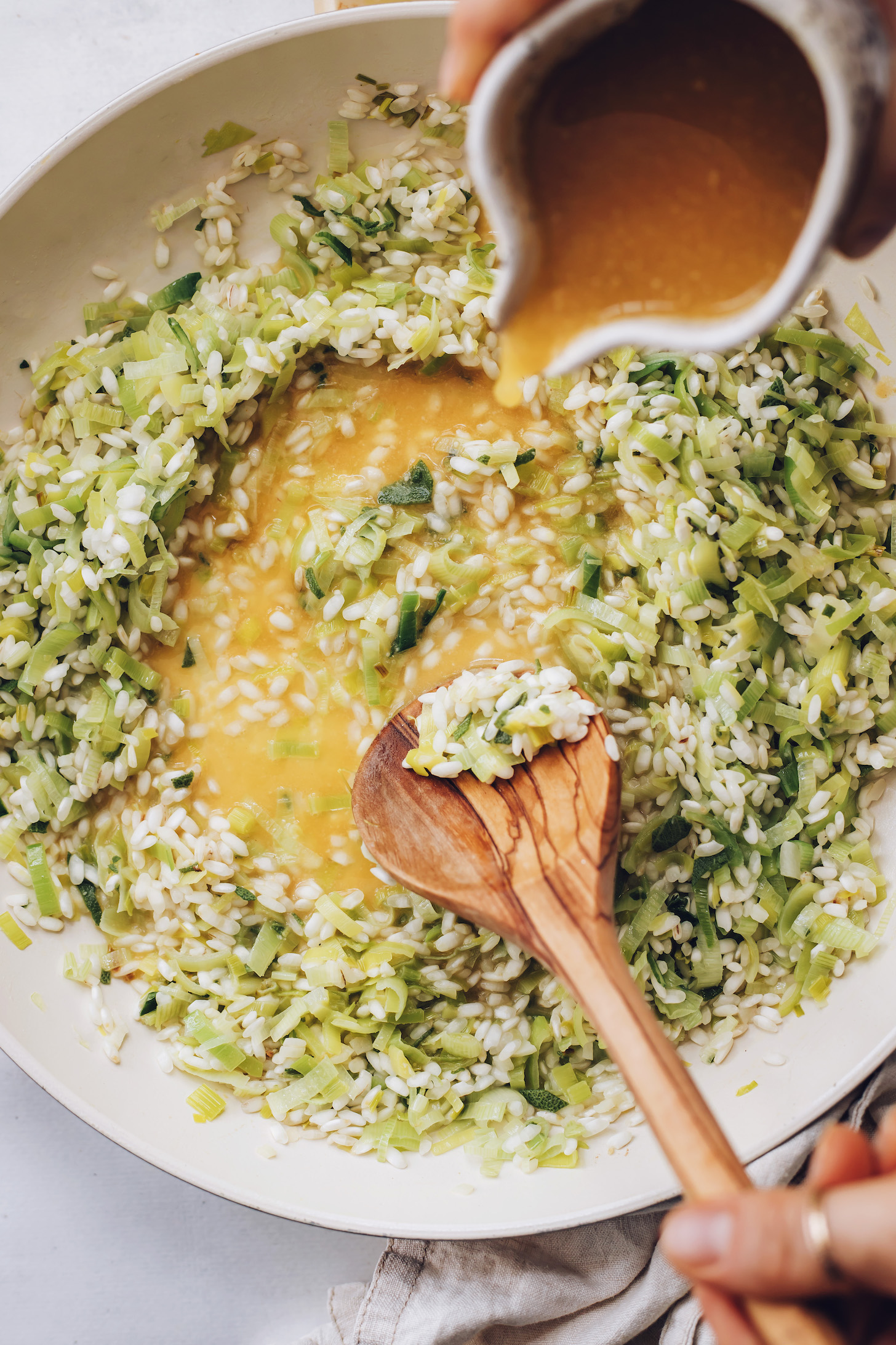 Pouring miso pumpkin broth over sautéed leeks, garlic, sage, and arborio rice