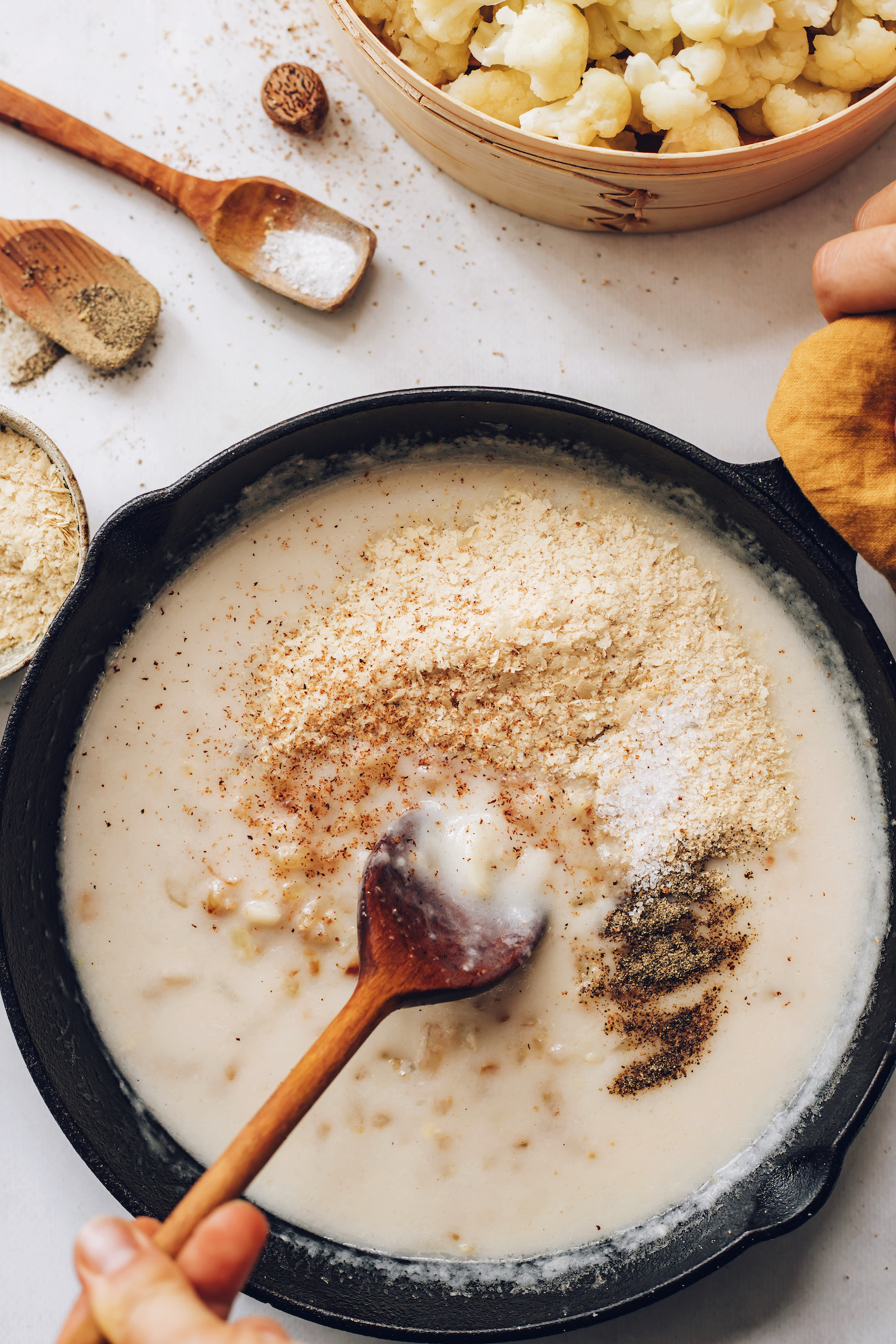 Nutritional yeast, nutmeg, salt, and black pepper sprinkled over a creamy vegan white sauce