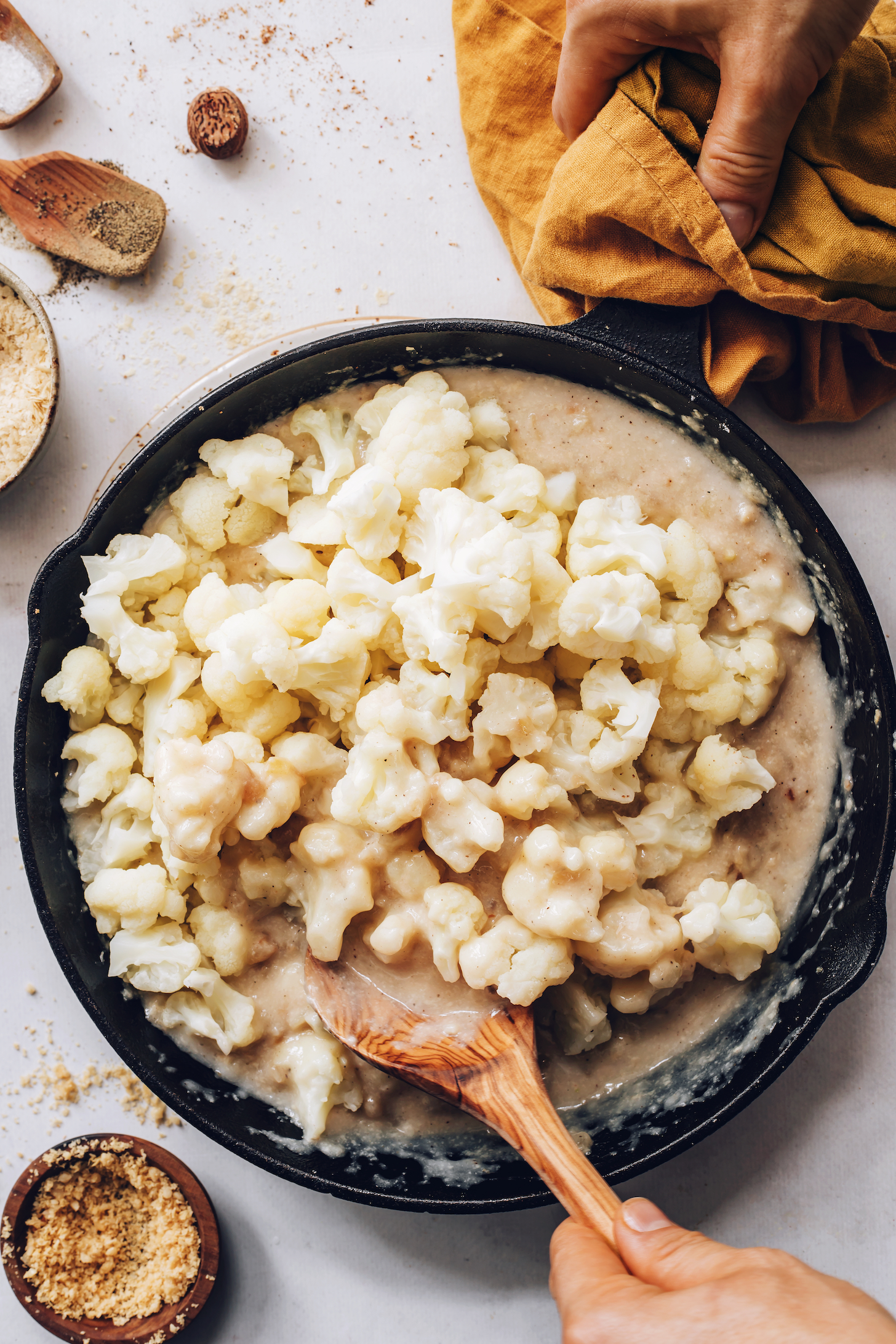 Stirring steamed cauliflower with vegan sauce