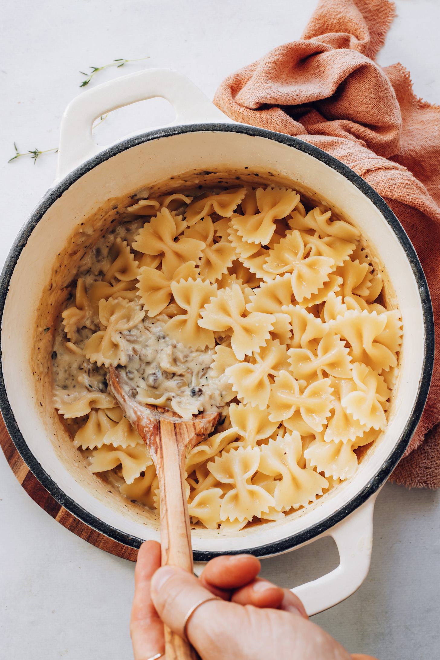 Stirring bowtie noodles and creamy mushroom sauce