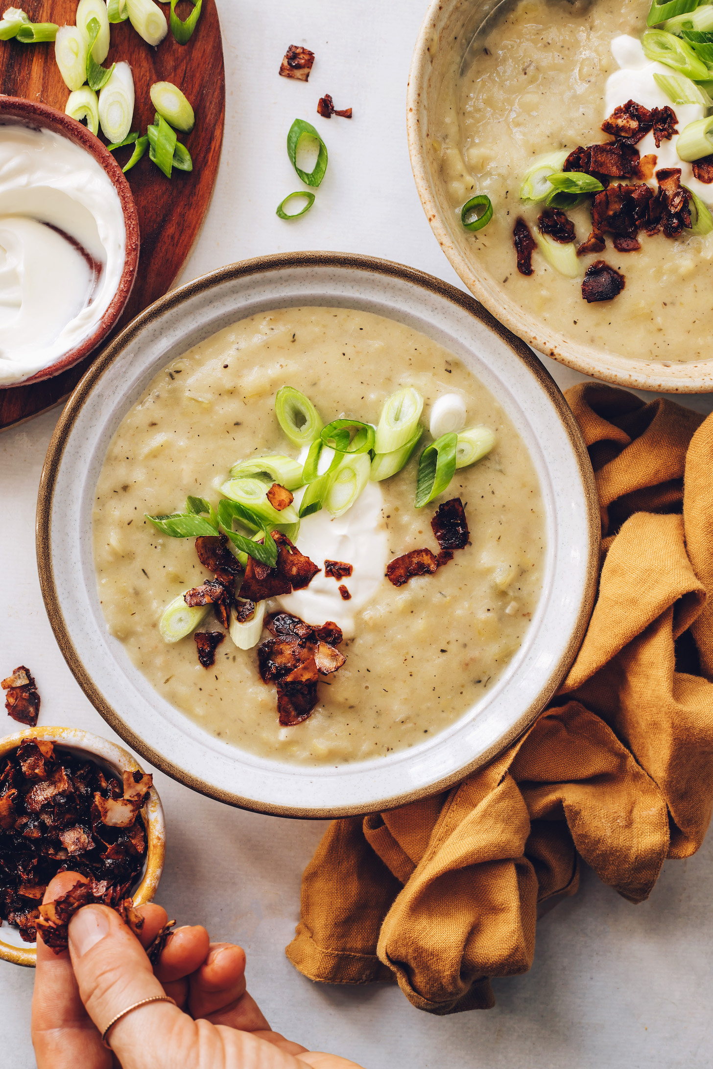 Sprinkling coconut bacon over a bowl of potato leek soup