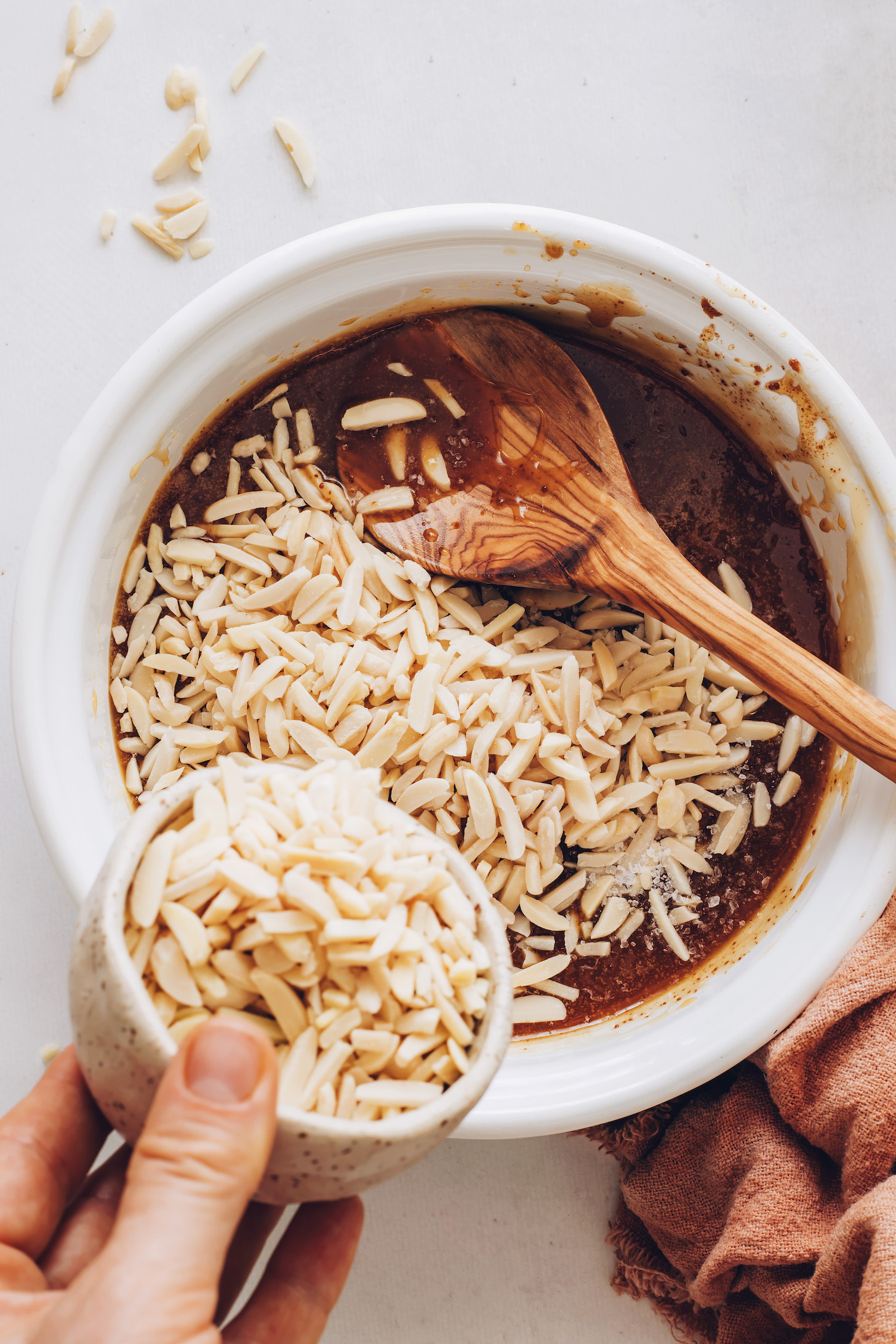 Adding almonds to a saucepan with melted coconut oil and natural sweeteners