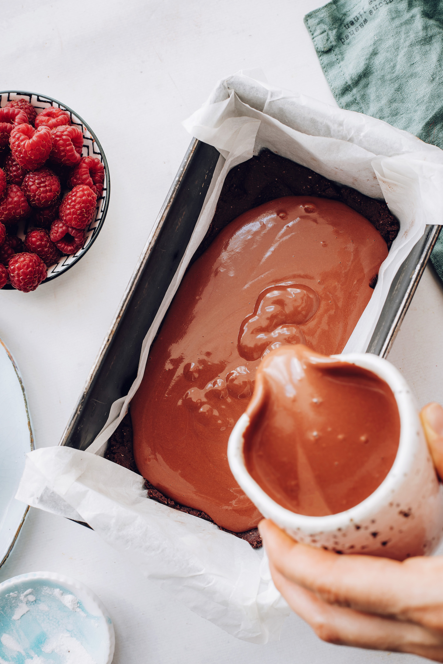 Pouring creamy vegan chocolate cheesecake filling into a pan