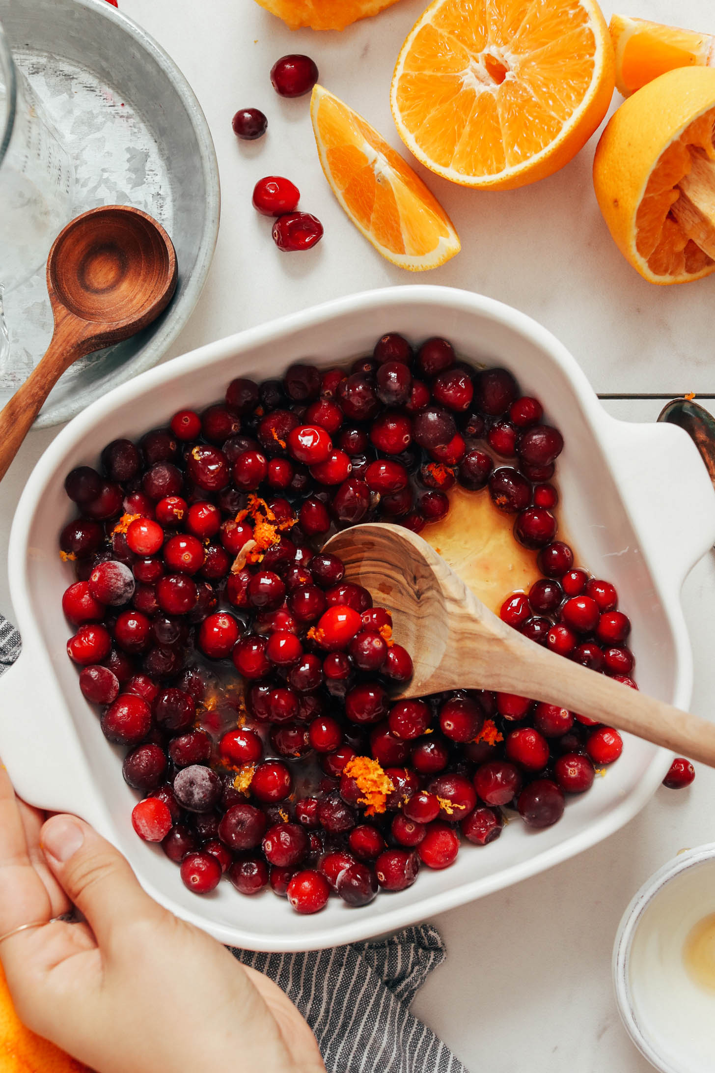 Stirring cranberries, orange juice, orange zest, and maple syrup in a baking dish