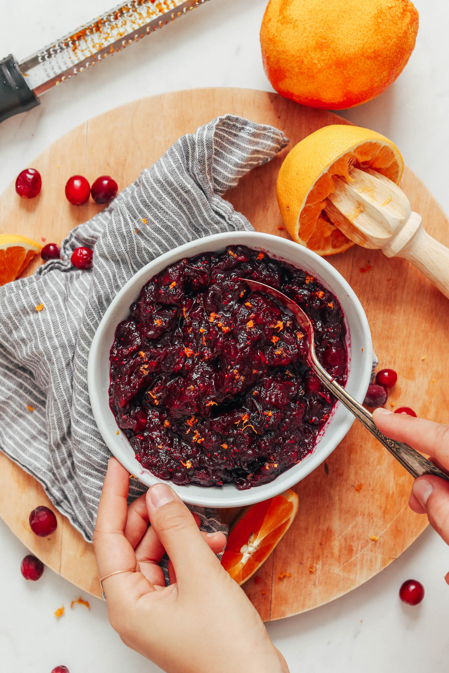 Spoon in a bowl of orange cranberry sauce with orange zest
