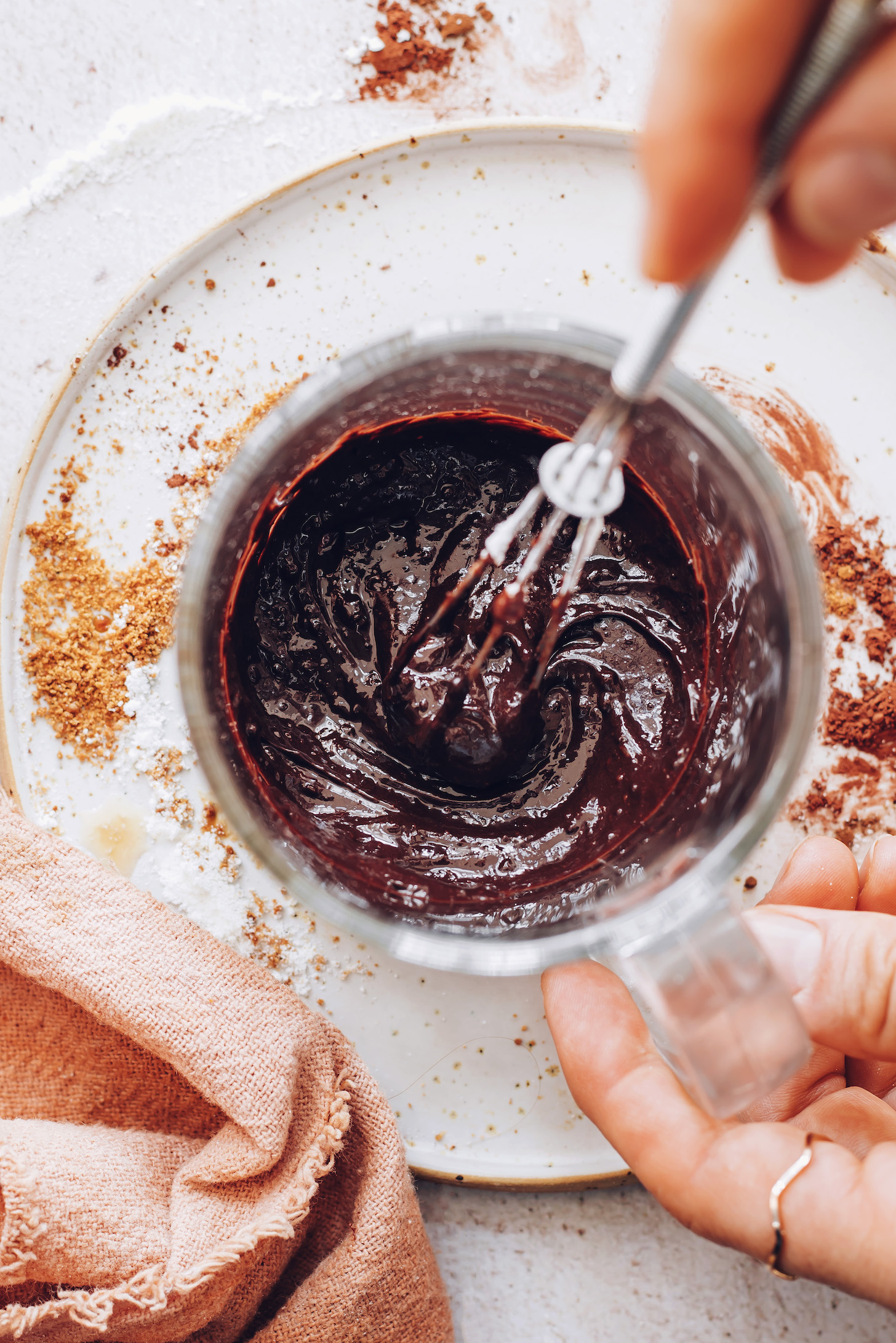 Mixing hot water with coconut milk powder, cocoa powder, and coconut sugar