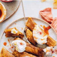 Plate of vegan and gluten-free apple butter dessert tamales with coconut whipped cream and cinnamon on top