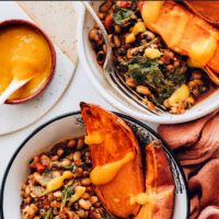 Hands holding a vegan and gluten-free black eyed pea nourish bowl with zesty mango habanero hot sauce on top