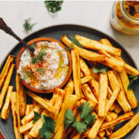 Plate of curry roasted parsnip fries with a dish of zesty dill yogurt sauce on the side