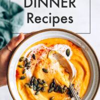 Bowl of warming vegan red lentil sweet potato soup with pumpkin seeds on top