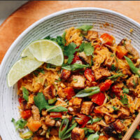 Plate of vegan and gluten-free spaghetti squash stir-fry with lime wedges and chopsticks on the side