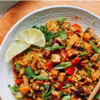 Plate of vegan and gluten-free spaghetti squash stir-fry with lime wedges and chopsticks on the side