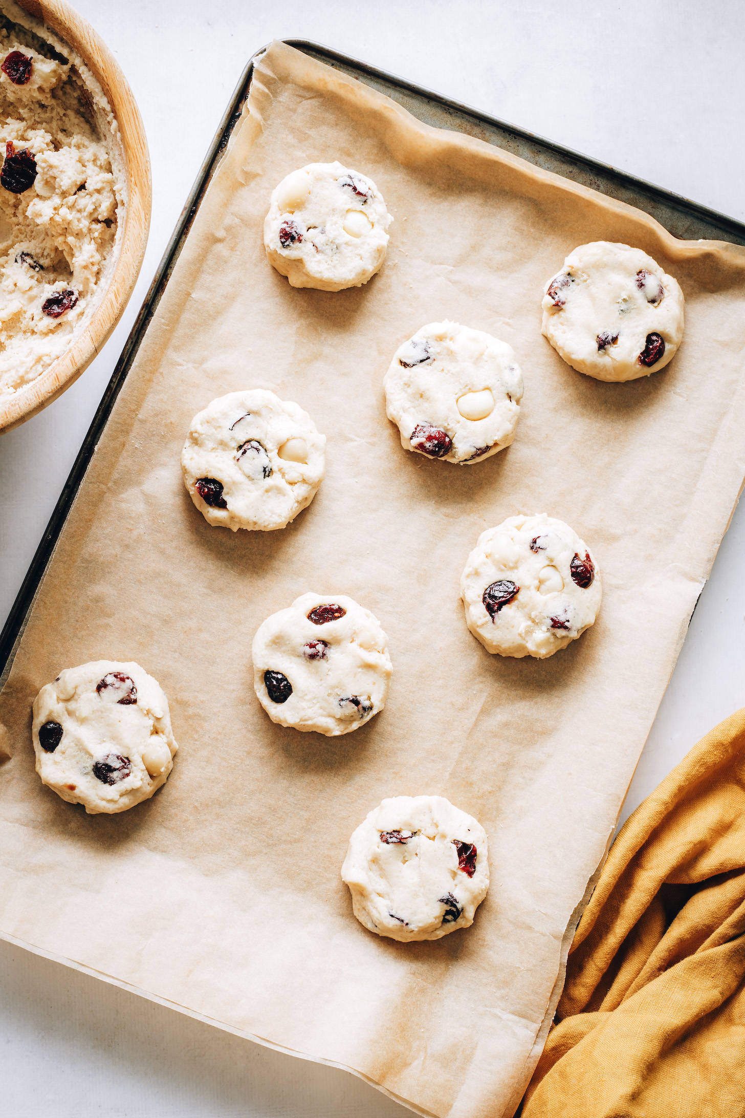 Unbaked macadamia nut cookie dough discs on a baking sheet