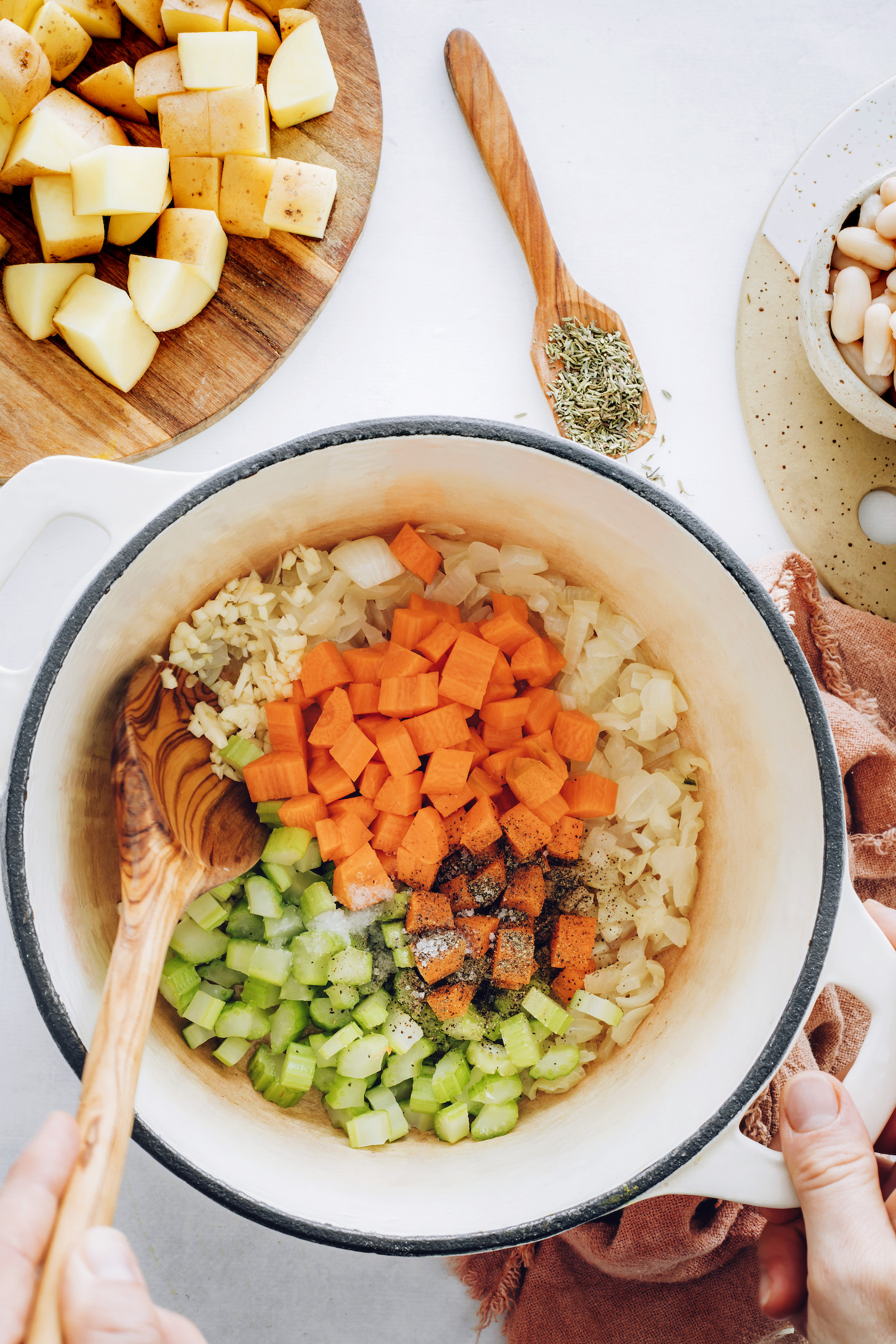 Sautéing onion, garlic, carrots, celery, salt, and pepper in a pot