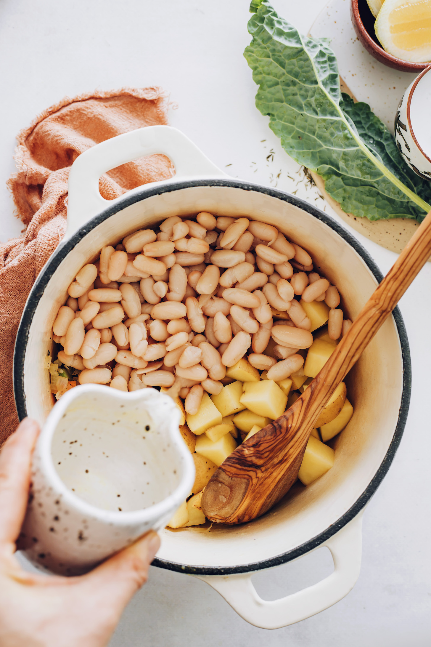 Pouring water over white beans and potatoes