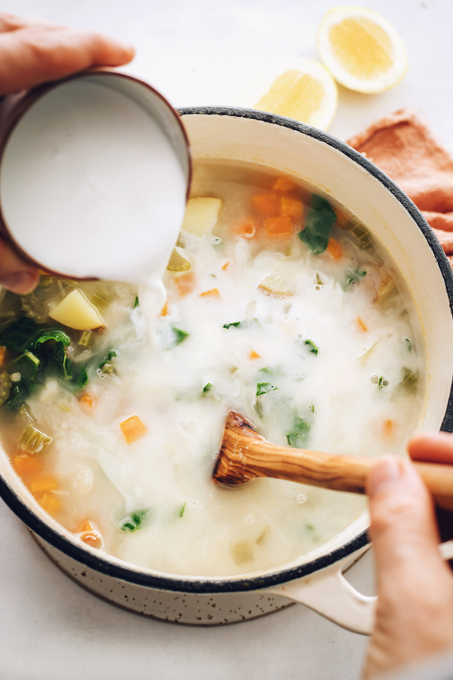 Pouring coconut milk into a pot of soup