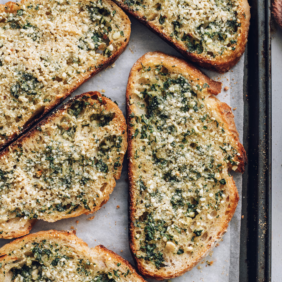 Close up shot of golden brown slices of vegan garlic bread on a baking sheet