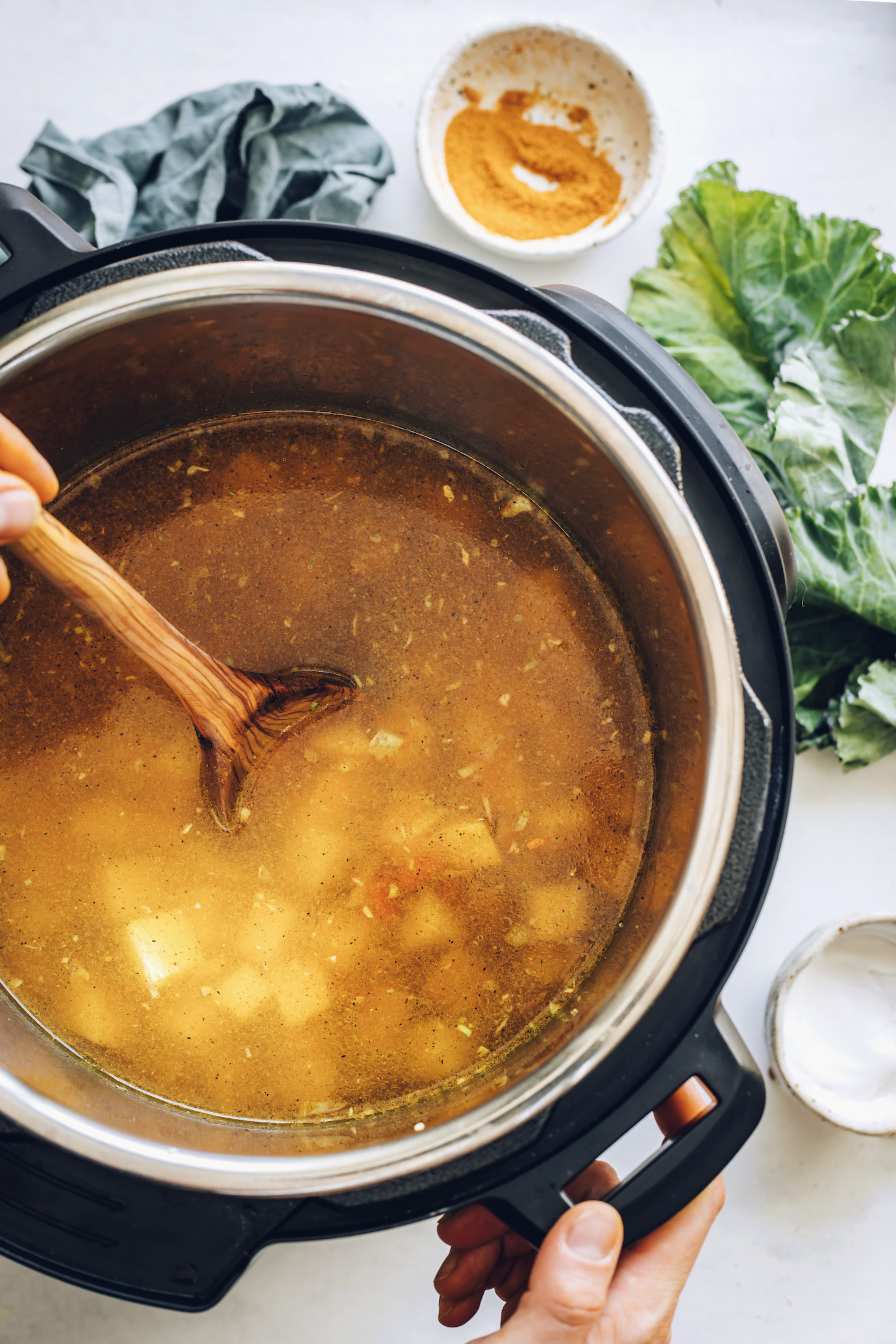 Golden vegetable broth in an Instant Pot with potatoes and carrots beneath the surface