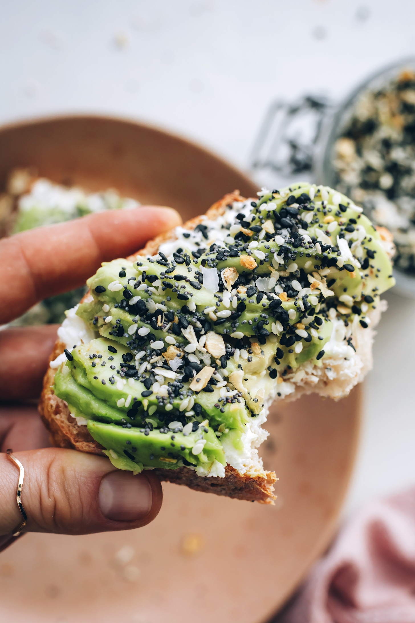 Holding a slice of avocado toast topped with Everything Bagel Seasoning