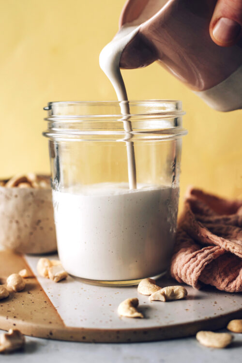 Pouring homemade cashew cream into a jar