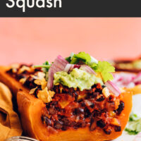 Plate of vegan and gluten-free enchilada-stuffed butternut squash with guacamole on top
