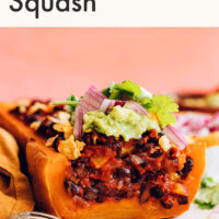 Plate of vegan and gluten-free enchilada-stuffed butternut squash with guacamole on top