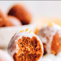 A vegan, gluten-free, no-bake pumpkin spice cake bite with a bite taken out of it