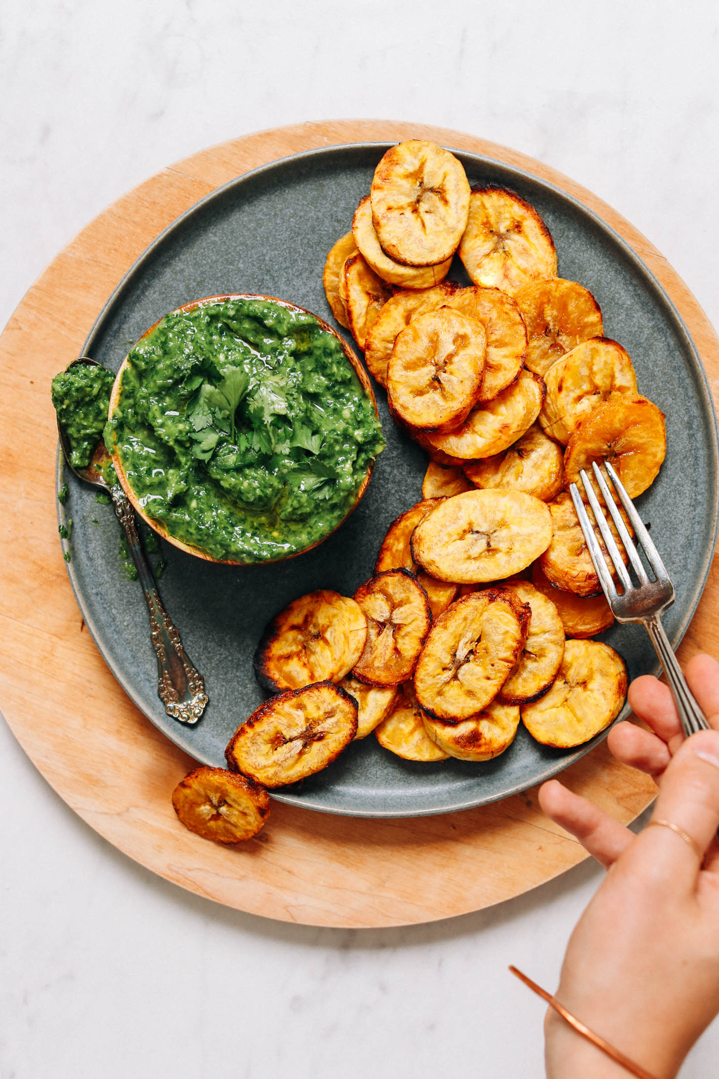 Using a fork to pick up a roasted plantain slice from a plate
