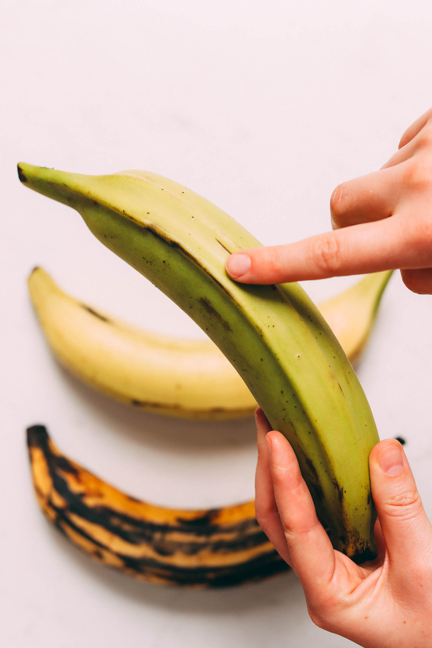 Pointing to a green plantain to show what it looks like if it was picked before it was mature