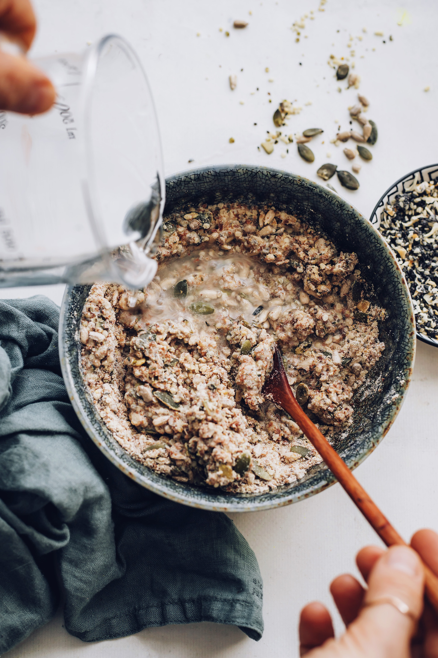 Adding boiling water to a bowl of seeds, brown rice flour, and salt