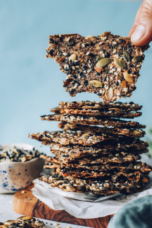 Holding a seed cracker beside a stack of more crackers