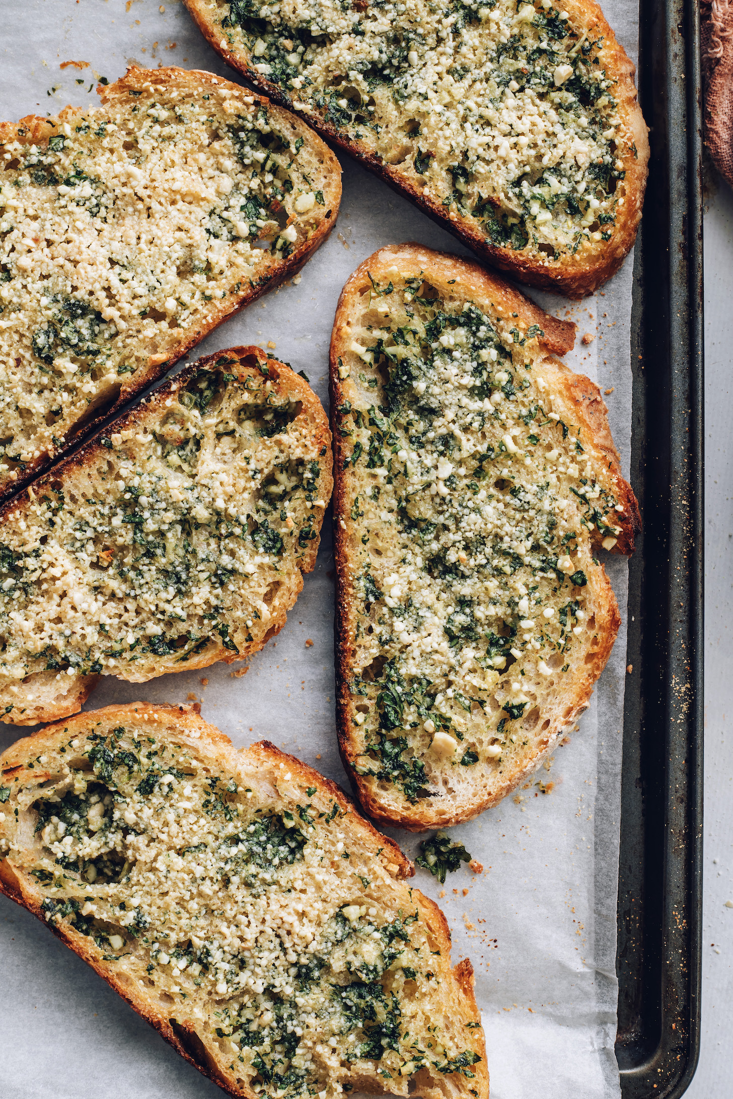 Slices of vegan garlic bread on a baking sheet