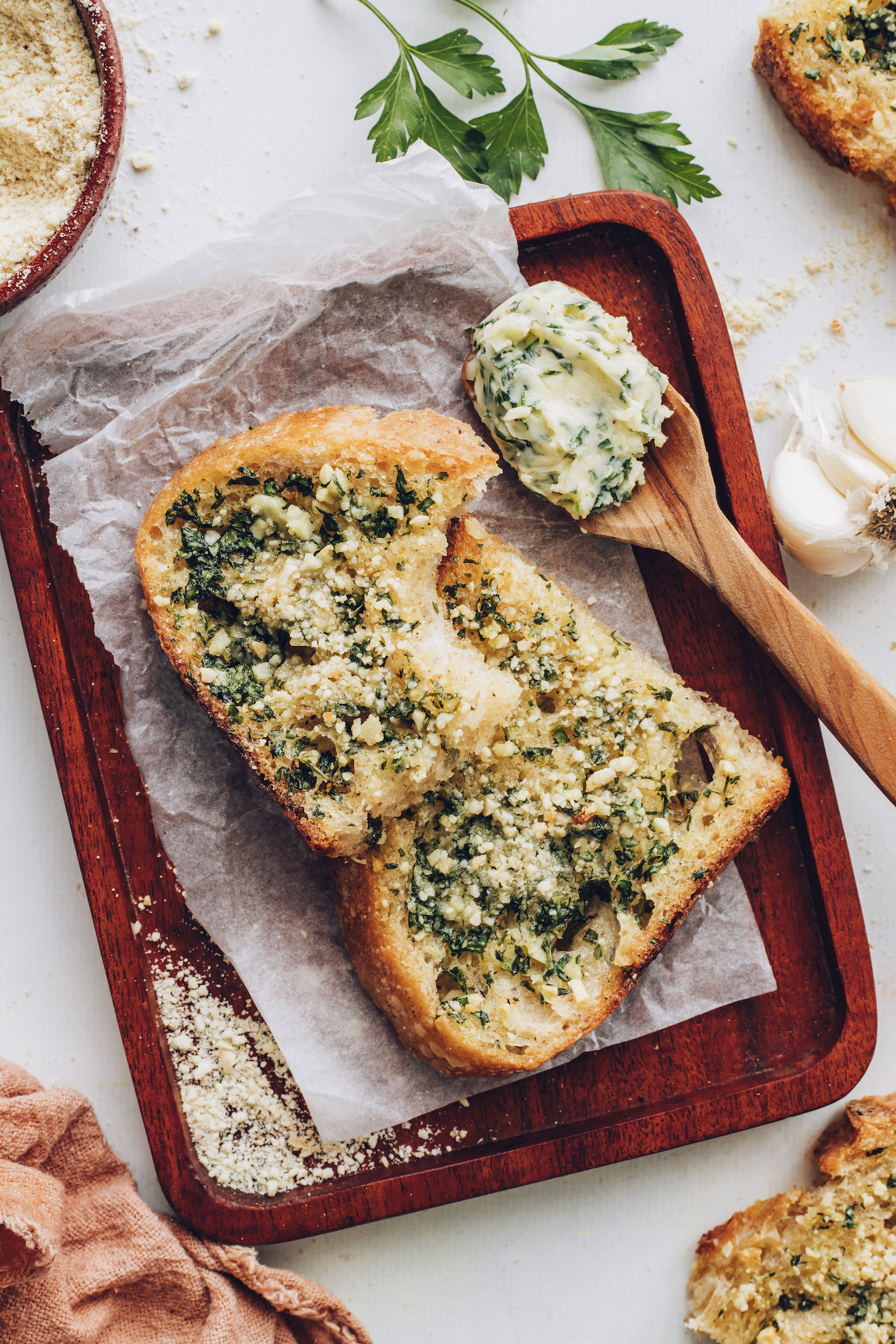 Vegan garlic bread on a wood plate lined with parchment paper