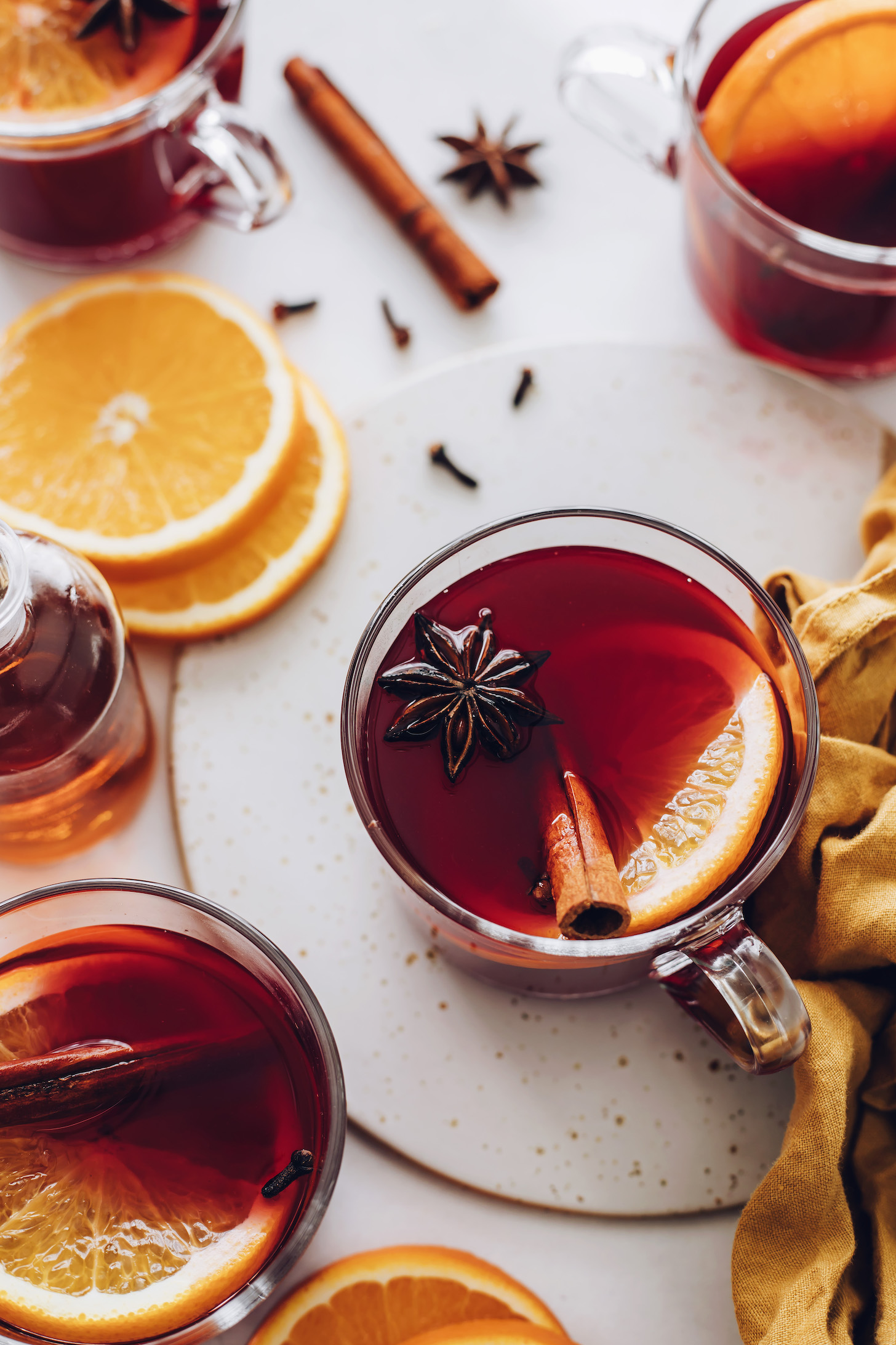 Star anise, cloves, and cinnamon sticks floating on mugs of tart cherry mulled "wine"