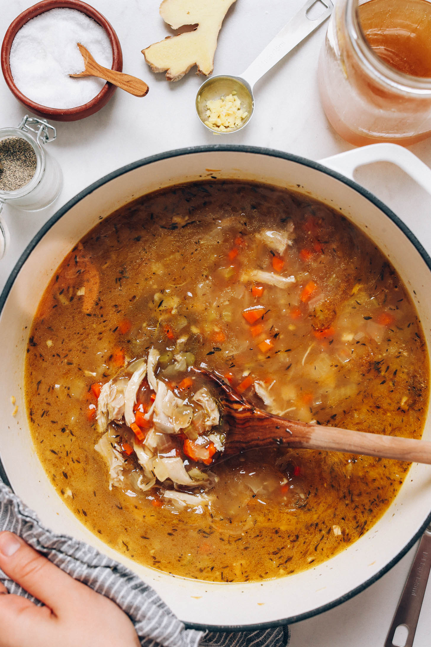 Stirring chicken noodle soup in a Dutch oven