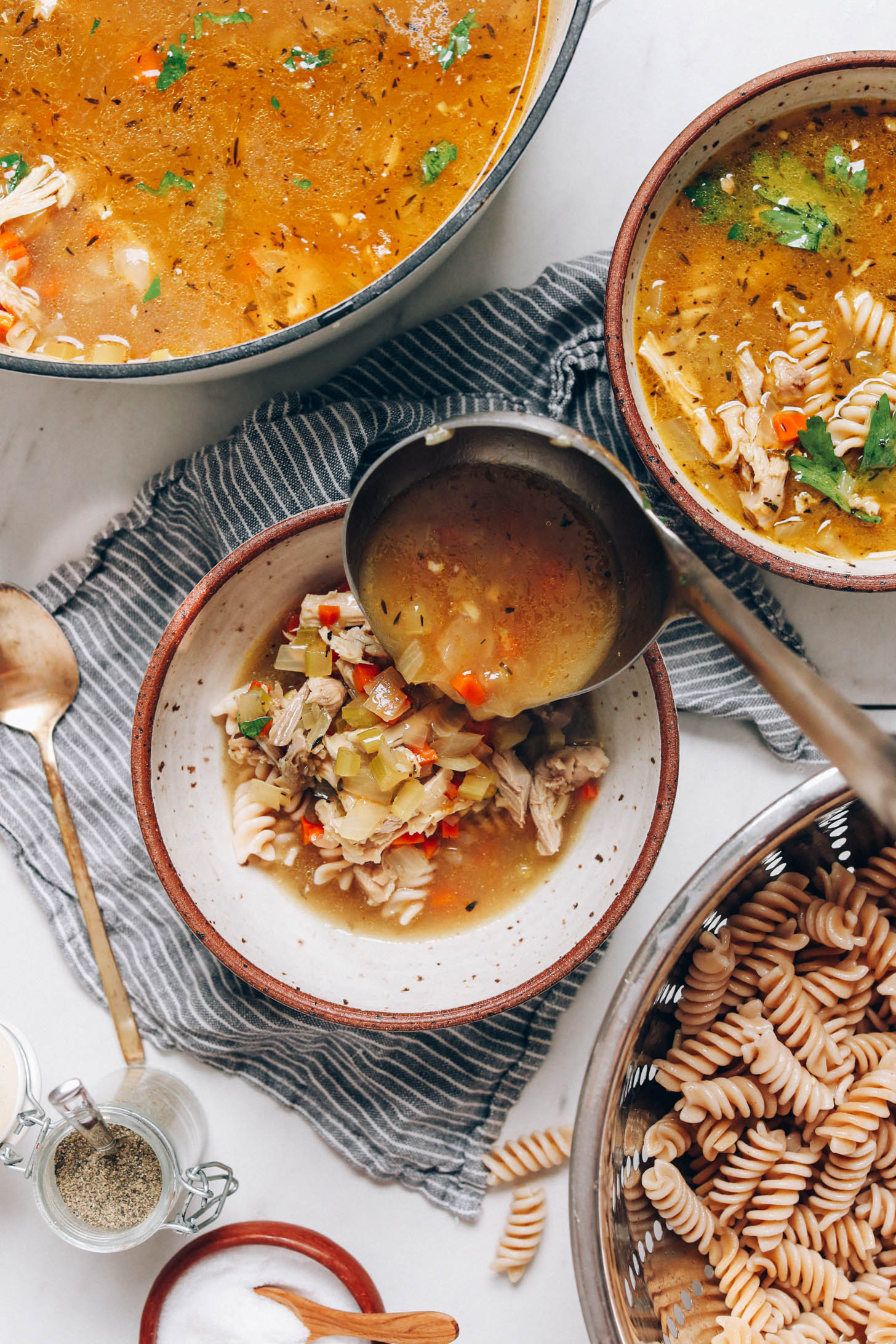Using a ladle to add chicken soup to noodles