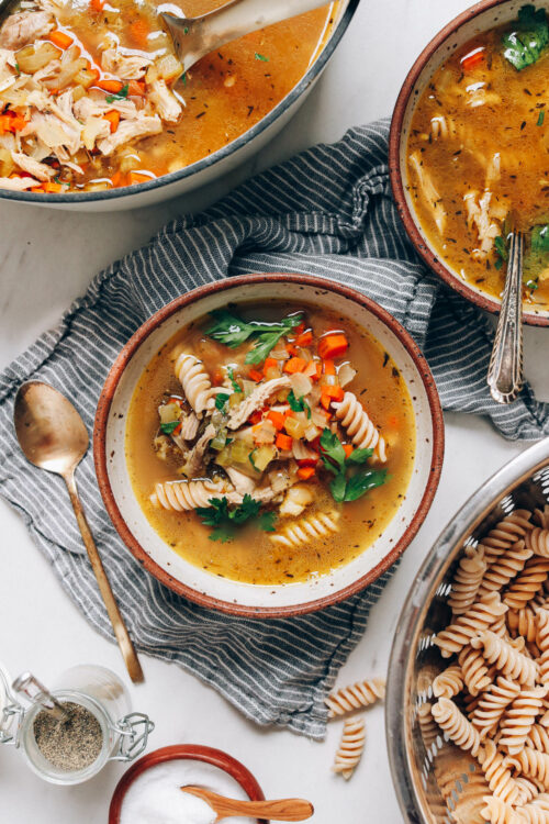 Bowls and a Dutch oven filled with chicken noodle soup